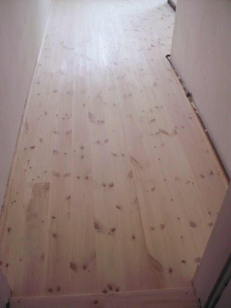 neuer Holzfußboden aus Kiefer-Dielenbrettern in einem Altbau. Dielung aus Nut-Feder-Brettern - oberflächenfertig lackiert und umlaufend mit Fußleisten versehen.